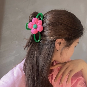 Détail d'une pince à cheveux fleur rose portée en coiffure demi-queue très élégante