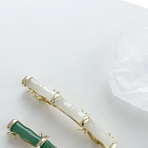 Détail de pinces à cheveux en forme de bambou, blanc crème et vert jade, feuilles d'or