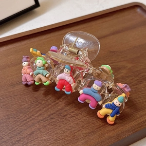 Détail d'une pince à cheveux avec cinq figurines de dessins animés colorées en tenue d'hiver