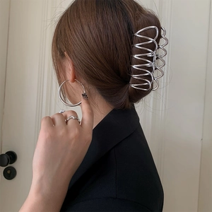 Vue détaillée d'une grande pince à cheveux ondulée en métal argenté sur chignon