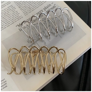 Vue détaillée des pinces à cheveux en métal doré et argenté avec design ondulé croisé