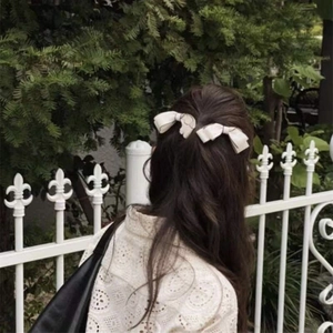 French retro white polka dot bow hair clips for women in a natural outdoor setting