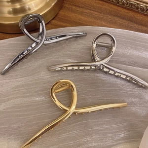 Trois grandes pinces à cheveux métalliques en argent, or et bronze sur tissu élégant