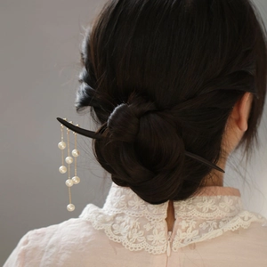 Detailed view of wooden hair stick with pearl tassels styled in an elegant updo hair bun