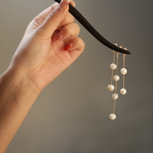Close-up of elegant long pearl tassel hanging from a classic wooden hairpin