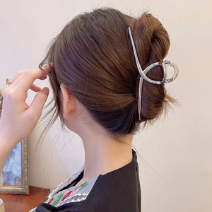 Vue latérale d'une grande pince à cheveux en métal argenté maintenant un chignon bas