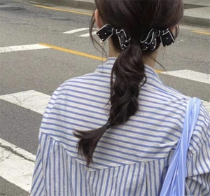 Close-up of black and white polka dot bow hair clips worn on a low ponytail