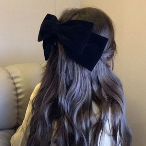 Elegant oversized black velvet bow hair clip shown from the back on long wavy hair