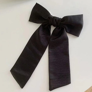 Vue détaillée du grand nœud papillon en satin noir avec de longs rubans élégants et fluides