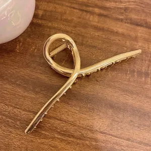 Détail d'une grande pince à cheveux en métal doré de 13,5 cm au design minimaliste torsadé