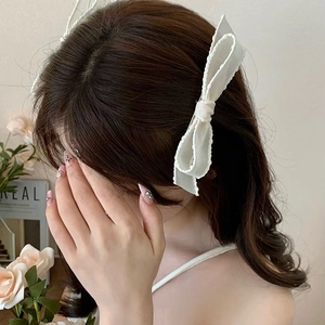 Close-up of elegant white mesh lace bow hair clips worn as side accessories on model