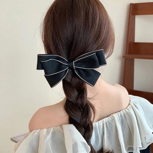 Elegante fermaglio per capelli a fiocco nero multistrato con bordo bianco su treccia mora