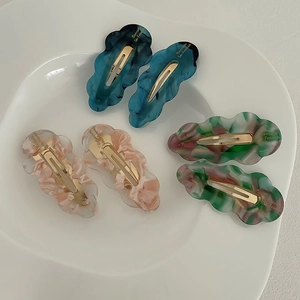 Detail showing marble patterned cloud hair clips with golden French label on ceramic tray