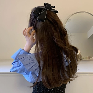 Dettaglio di un fermaglio per capelli con fiocco nero e bordo bianco su capelli lunghi