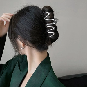 Elegant wavy silver metal hair claw clip for women shown on a stylish bun hairstyle