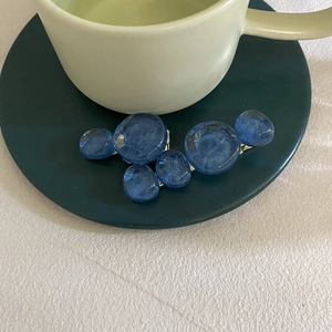 Detail of two vintage blue crystal hair clips resting on a green ceramic cup edge