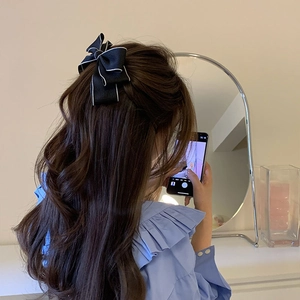 Elegante fermaglio per capelli a fiocco nero con bordo bianco su capelli mossi