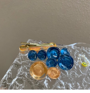 Detailed close-up of blue and orange resin hair clip on textured glass tray