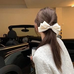 Elegante fiocco per capelli color crema indossato da una modella in un set di lusso