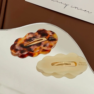 Close-up of cloud-shaped acetate hair clips in tortoiseshell and cream on wave mirror