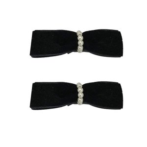 Elegant pair of black velvet bow hair clips with white pearls on a white background