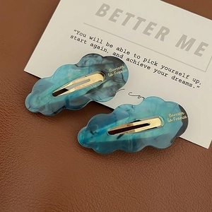 Detail view of blue marble acetate cloud hair clips with golden French brand lettering