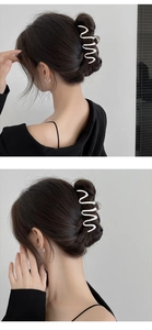 Detail of silver wavy metal hair claw clip showing textured grip on a hair bun