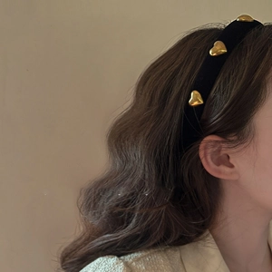 Detail of a vintage black velvet headband with three gold heart-shaped metal accents