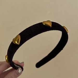Detail of handmade black velvet headband with golden metal heart studs and inner label