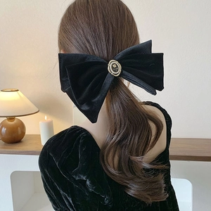 Vue détaillée du nœud en velours noir avec emblème de rose bordé de perles