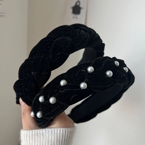 Close-up of black velvet braided headbands with pearl accents and elegant retro design