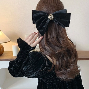 Détail du grand nœud papillon en velours noir avec ornement de blason rose doré vintage