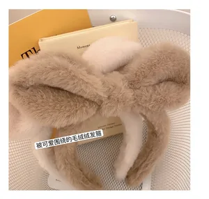 Close-up of fluffy plush bow headbands in beige and khaki within a decorative basket