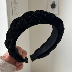 Detail of hand-held black velvet braided headband with thick texture and classic weave