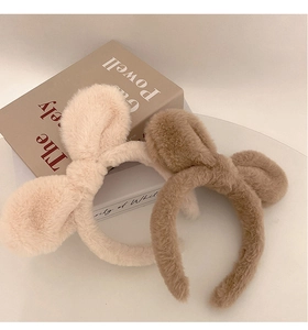 Close-up of plush rabbit ear headbands in beige and brown with soft faux fur texture