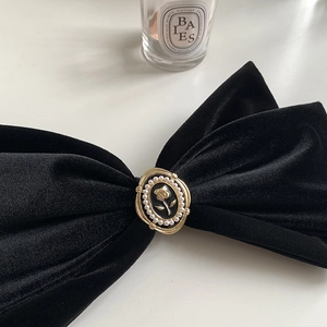 Détail de la grande barrette à nœud en velours noir avec ornement rose perle et bord doré