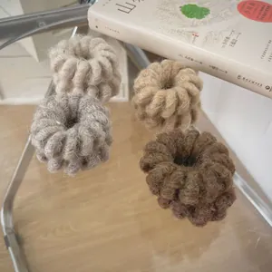 Détail de quatre élastiques en laine aux tons terreux avec une texture de maille torsadée