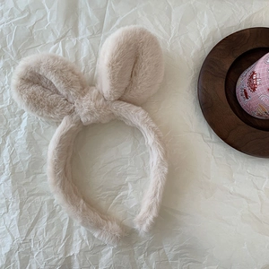 Macro detail of beige plush rabbit ear headband with soft fluffy texture on white background