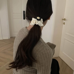Elegant cream ruffled scrunchie with a sunflower accent on a woman's ponytail hair