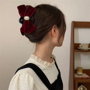 Gros plan d'une pince à cheveux en velours bordeaux avec perle sur une femme