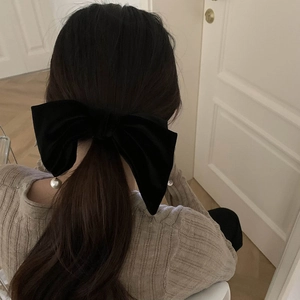 Dettaglio di un grande fiocco per capelli in velluto nero con una perla bianca decorativa