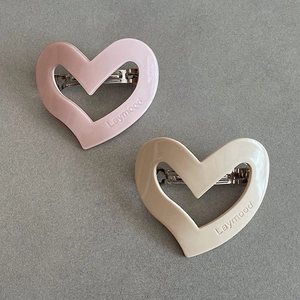 Detailed macro view of heart-shaped cream hair clips with Laymood engraving and silver spring