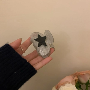 Detailed view of a grey glitter star hair claw clip held by a hand for size reference