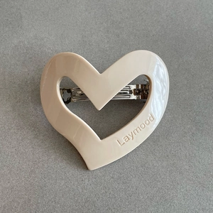Close-up of cream heart hair clip with silver metal spring and Laymood engraving
