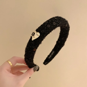 Dettaglio della trama in tessuto tweed e stemma a cuore dorato con numero 5 su cerchietto nero