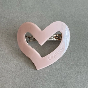 Detail showing a cream pink heart hair clip with embossed Laymood text and silver clip