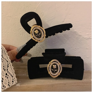 Detail of vintage black velvet hair claw clip with golden rose and pearl accents