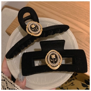 Elegant black velvet rose hair claws set with faux pearls and gold details in a white dish