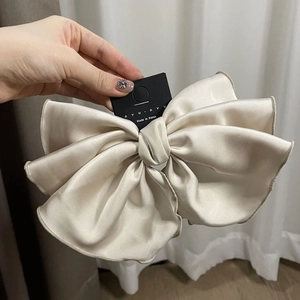 Détail d'un grand nœud papillon en satin champagne montrant la texture soyeuse du tissu