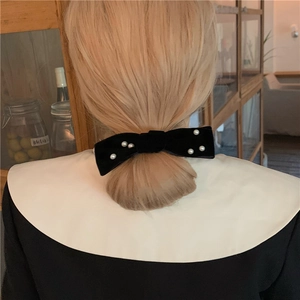 Elegant black velvet bow hair clip with pearls worn on blonde hair for a retro French look